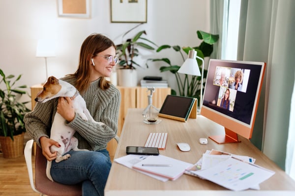 woman at home holding a dog looking at a computer screen