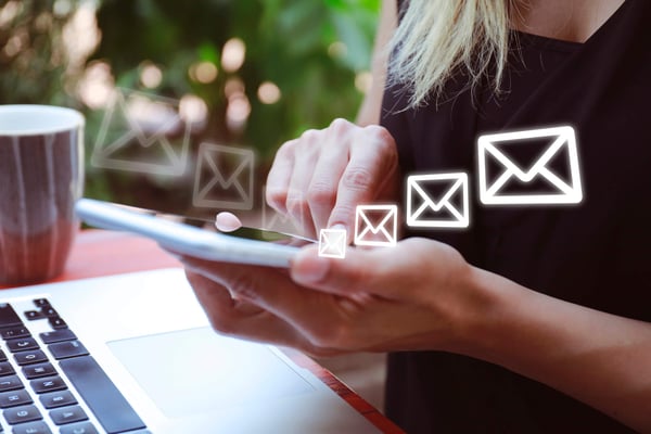 person sitter framför dator och skriver på mobil