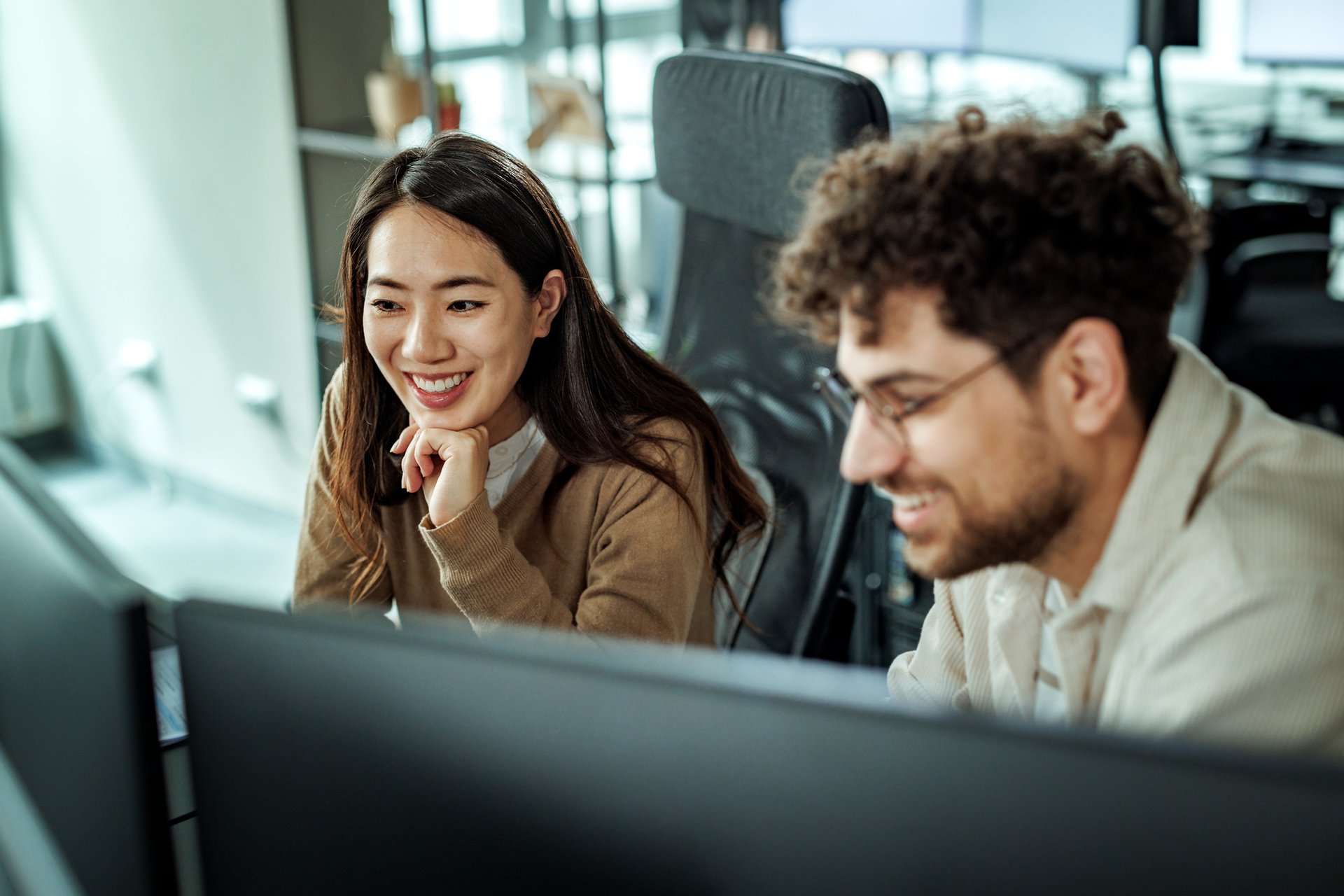 Woman and man sitting next to each other, smiling and looking at a computer screen.