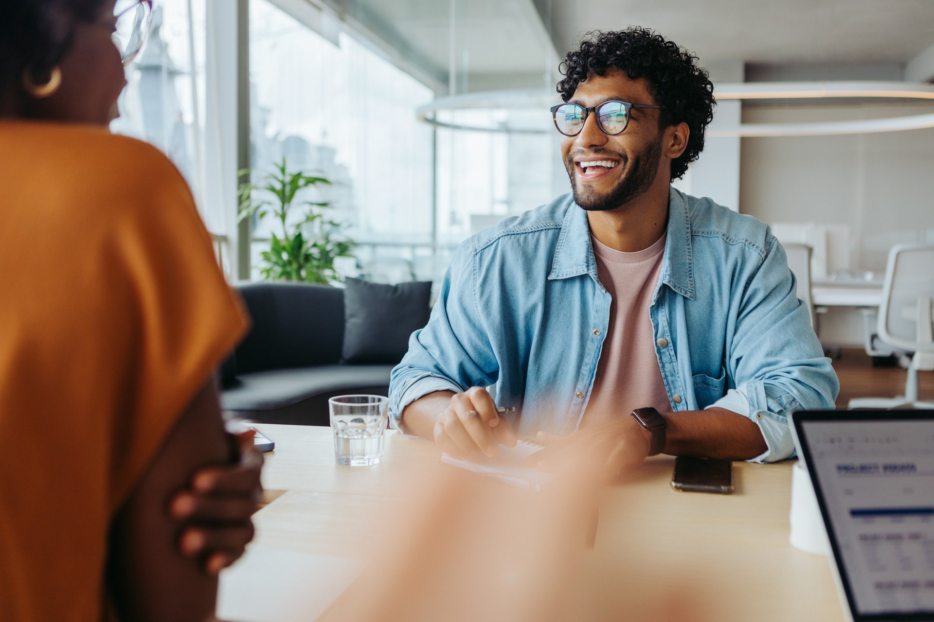 Smiling man and woman in conversation in an office environment.