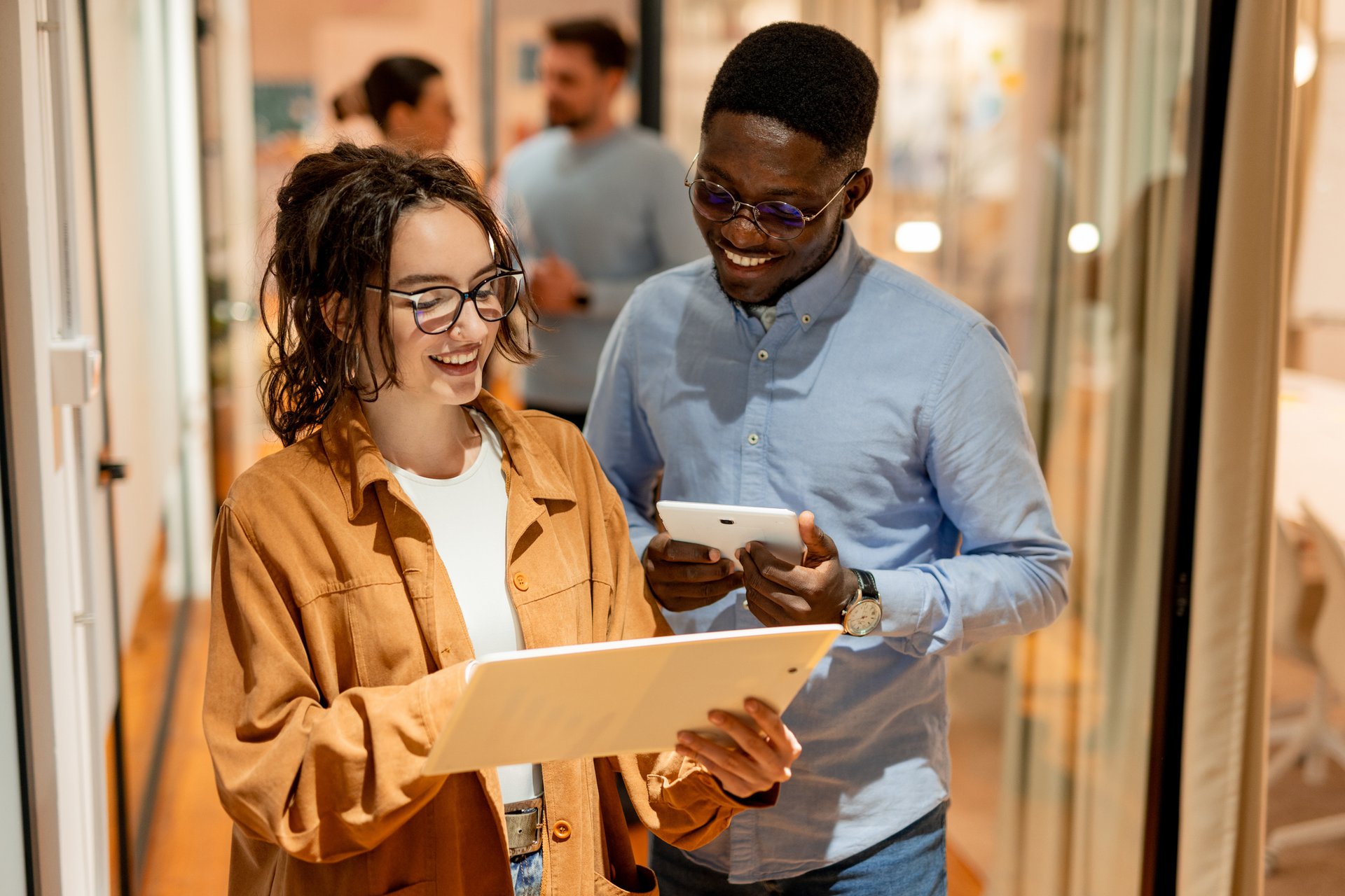Ung kvinna och man ler och tittar på en surfplatta.