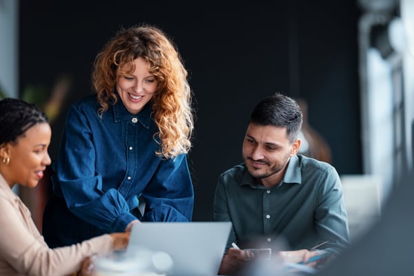 A man and a woman collaborating at a computer in an office setting, representing work related to the EU Pay Transparency Directive.